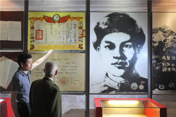 图为邱少云弟弟邱少华(右)和邱少云侄儿邱光兵(左)经常到重庆邱少云烈士事迹陈列馆参观,墙上是邱少云画像和中朝两国向邱少云颁发的英雄证书放大版(2015年5月18日摄)图片